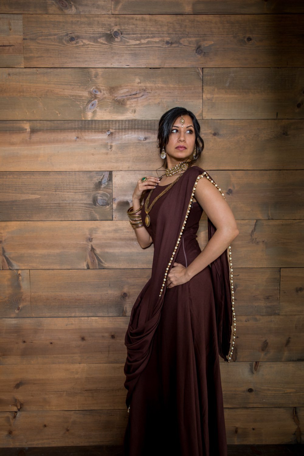 Model in a deep brown saree with gold trim